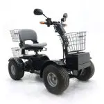 Black four-wheeled electric mobility scooter with wide tires, a cushioned seat, rear and front wire baskets, and handlebar mirrors, designed for all-terrain use