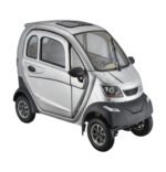 A compact, silver-colored, enclosed three-wheeled electric vehicle with black accents. It features a front windshield, doors with transparent windows, and a small front grille. The vehicle has a modern, streamlined design suitable for urban transportation.