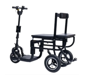 The image shows an eFOLDi Lite Mobility Scooter, featuring three wheels: two larger ones at the back and a smaller one in the front. The scooter has a black frame with a textured footplate for grip and a large, padded seat without a backrest. It includes a vertical post at the rear end, which might serve as a backrest or support handle. The front includes an adjustable handlebar column with handgrips and controls. The overall design suggests a focus on stability and comfort, with a portable and foldable structure for ease of transportation.