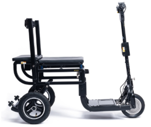 The image features an eFOLDi mobility scooter in a folded state, showcasing its compact design. It is predominantly black with some metallic and yellow accent details that likely indicate functional components or safety features. The scooter has a substantial rear wheel and a smaller front wheel, both with black tires and silver rims. There is a large, black padded seat with a backrest that appears to be foldable. The steering column, which has handgrips and control mechanisms, is vertical and seems to be adjustable. This design emphasizes the scooter's portability and ease of storage.