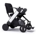 Whill Model F wheelchair with White armrests, equipped with sturdy wheels and a practical under-seat storage basket.