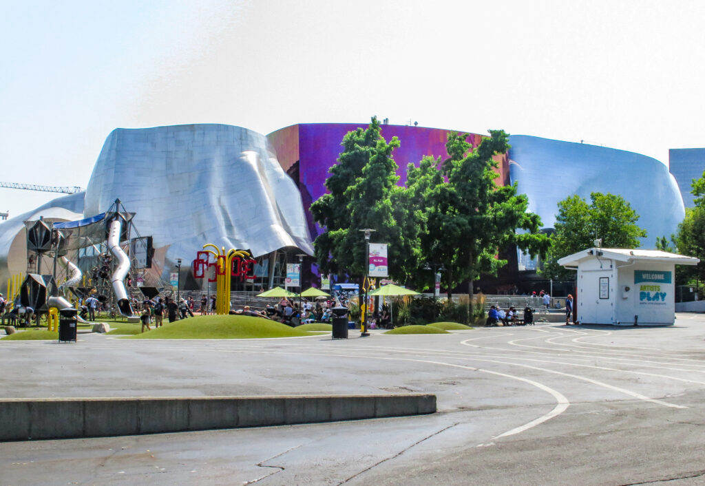 The Museum of Pop Culture in Seattle with its distinctive, colorful architecture, under a clear sky with visitors enjoying the outdoor playground.
