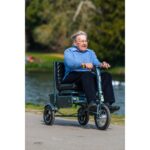 Elderly man enjoying a ride on the eFOLDi Explorer scooter by a tranquil lakeside, emphasizing the scooter's ability to provide independence and enjoyment in outdoor recreational spaces.