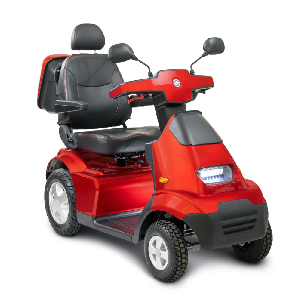 A bright red, four-wheeled mobility scooter with a comfortable black seat, armrests, and backrest. The scooter has rearview mirrors, a headlight, and a sturdy build suitable for outdoor use. It features large, rugged tires for stability on various terrains.