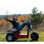 Woman lounging on red Daymak Boomerbeast 2D in an open field.