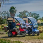 Live Style Image Side View of Red Afiscooter S3 Mobility Scooter with Canopy Golf Tires, Blue Afiscooter S4 with Canopy Mobility Scooter