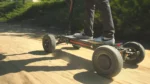 Man riding CycleBoard X-Quad 3000 all terrain electric scooter on a dirt trail