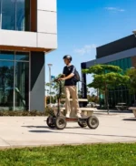 Man riding CycleBoard X-Quad 3000 electric scooter in an urban outdoor area