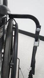 Close up of the Tilt N Tote hold down arm and cam buckle securing strap over the rear wheel