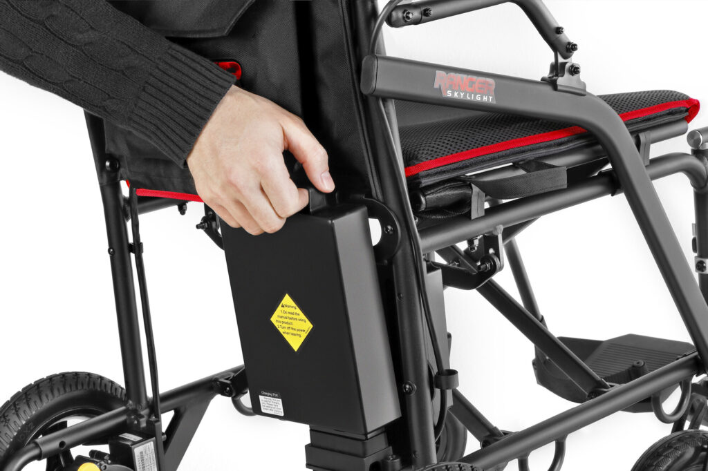 Porto Mobility Ranger Skylight folding power wheelchair, hand lifting the black pack from behind the backrest