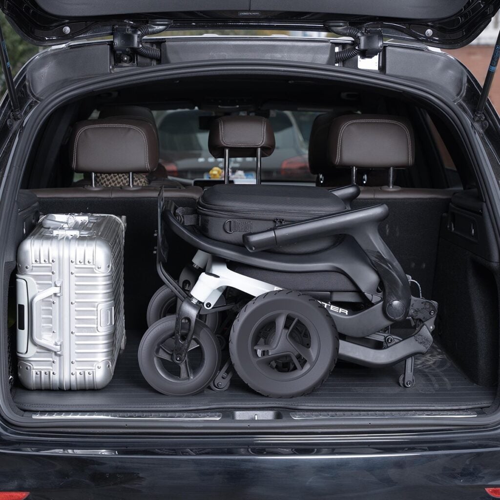 Folded Robooter E80 in a car trunk next to a suitcase